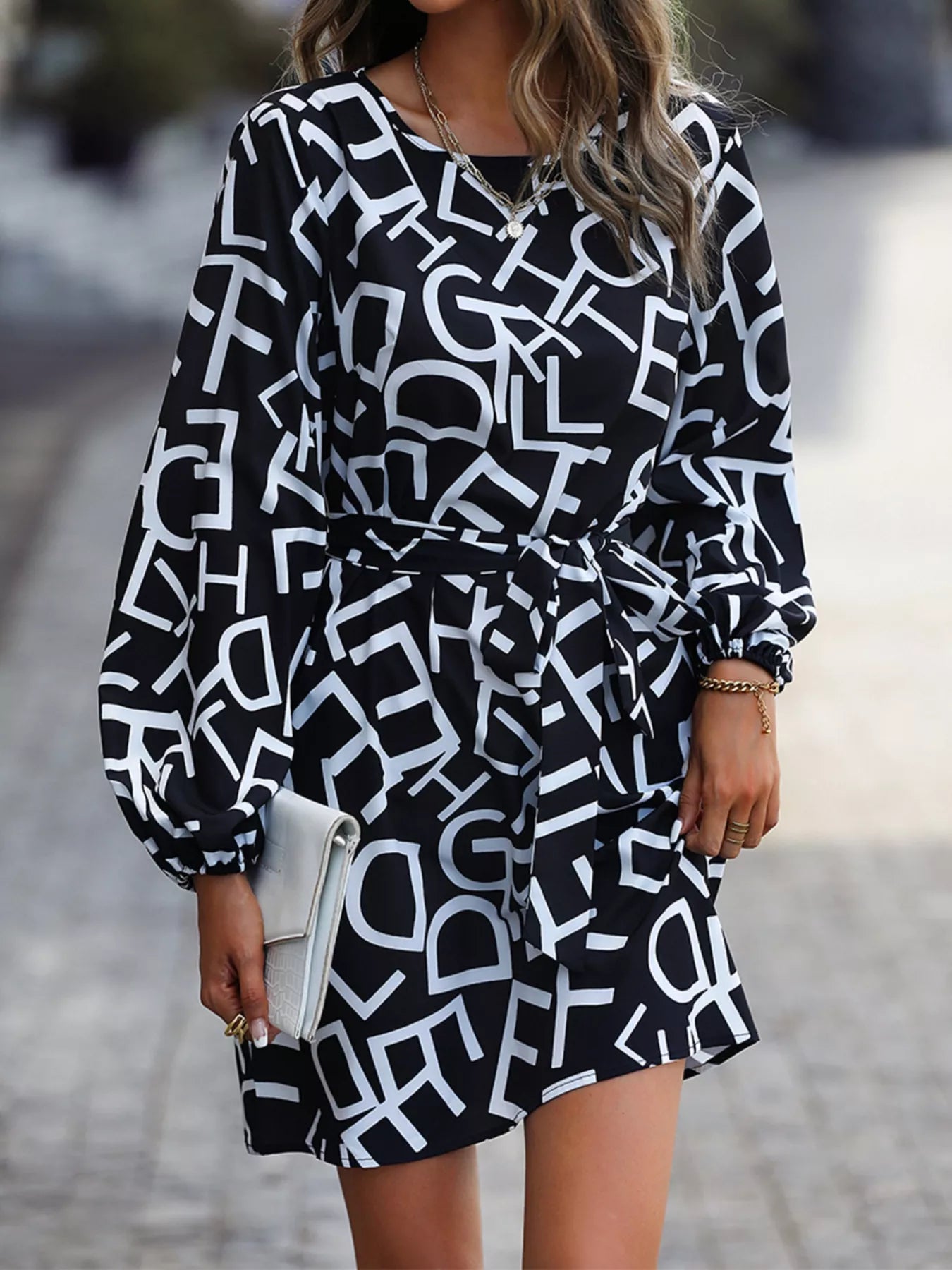 NEWYORKLISTED STYLE COLLECTION: Woman wearing a black and white patterned dress on a blurred street background
