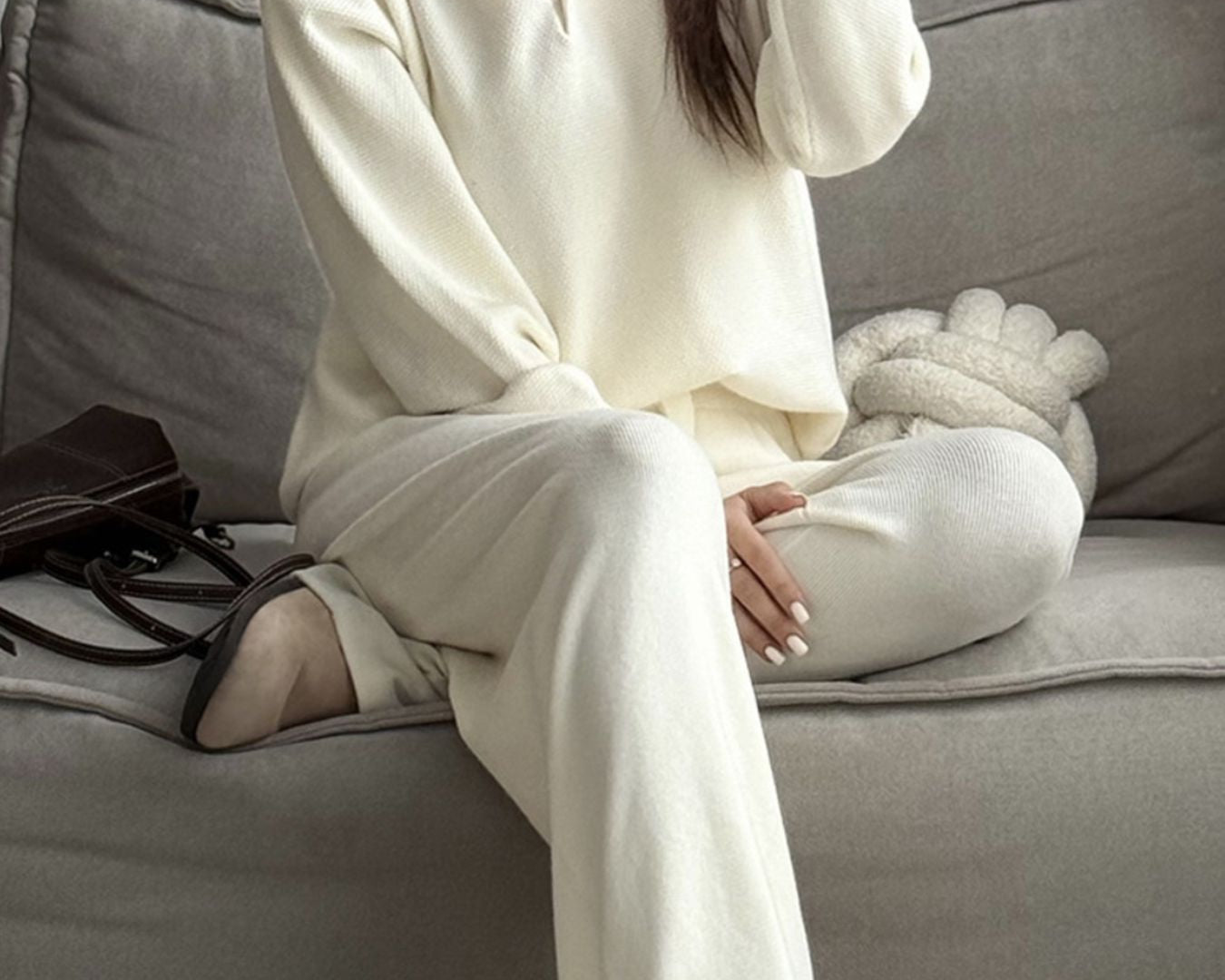 NEWYORKLISTED Comfort Collection: Person wearing a white outfit sitting on a gray couch.
