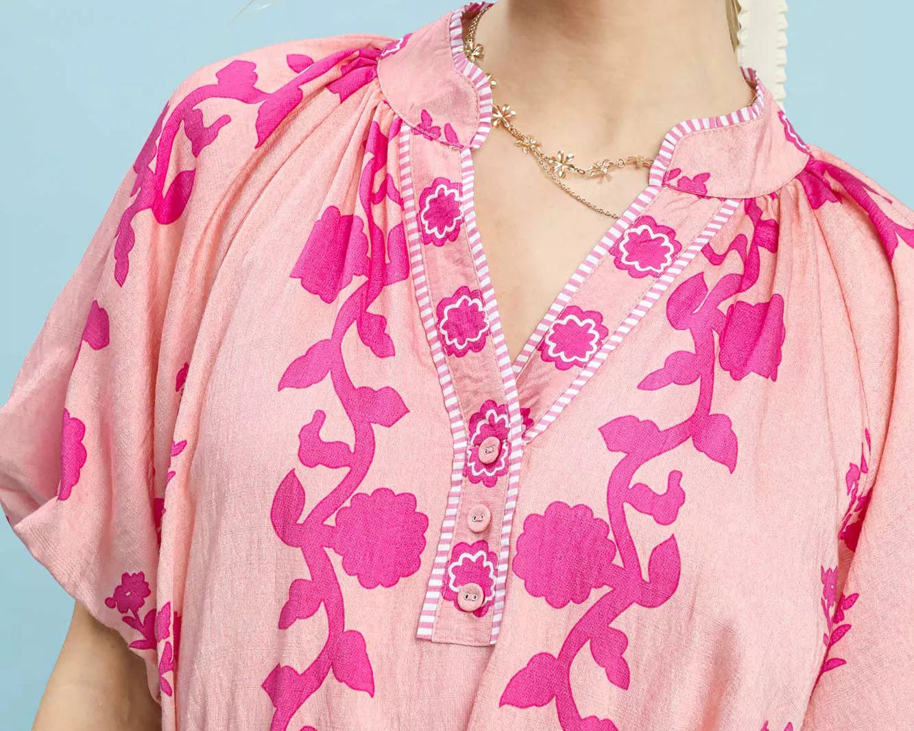 NEWYORKLISTED STYLE COLLECTION: Woman wearing a pink floral dress against a light blue background
