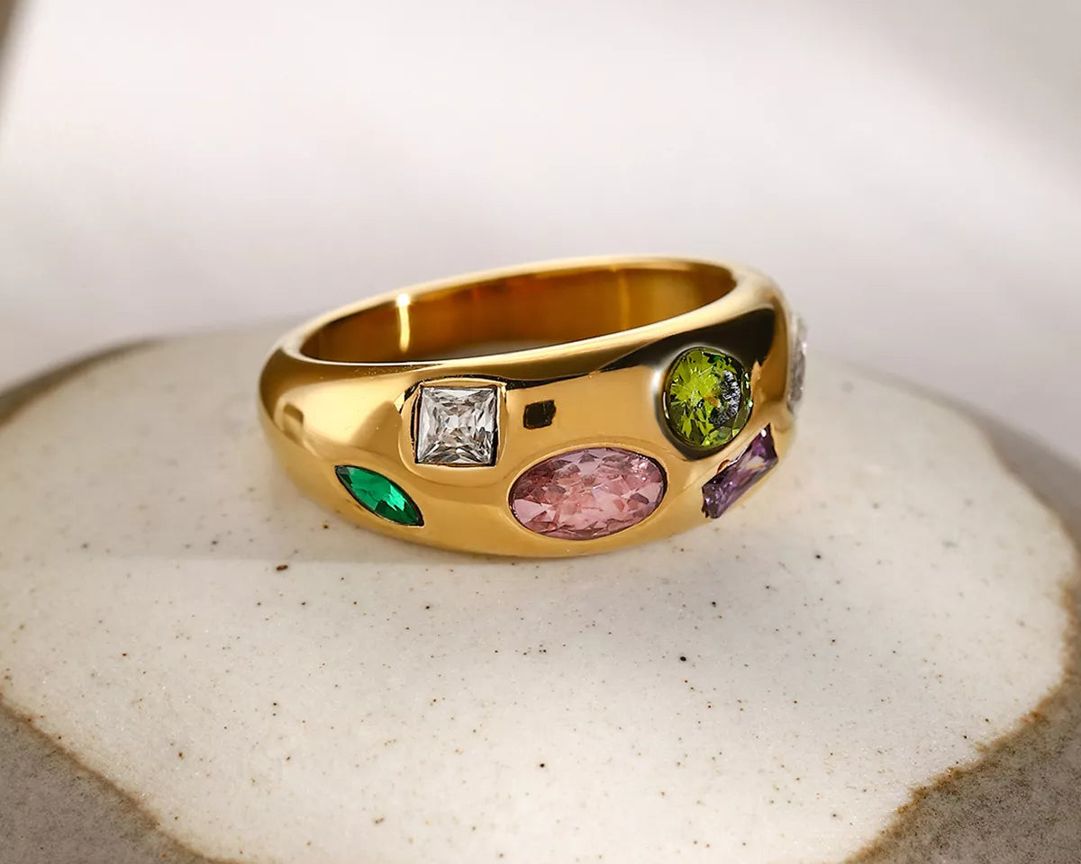NYLD Glamour Collection by NEWYORKLISTED: Gold ring with colorful gemstones on a textured surface