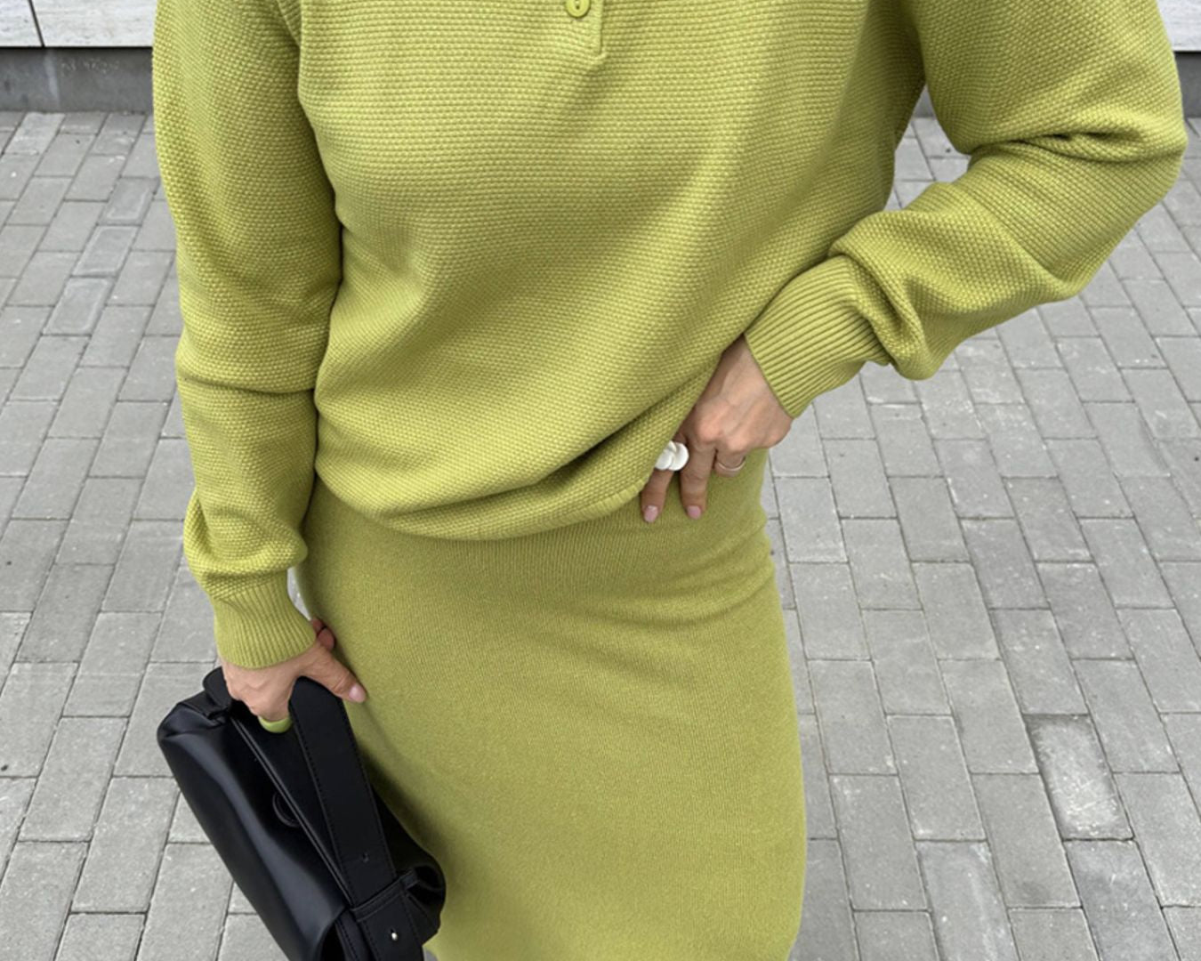 NEWYORKLISTED Comfort Collection: Person wearing a green outfit with a skirt and sweater on a tiled pavement.
