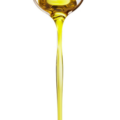 Spoon pouring a stream of NEWYORKLISTED Castor Oil likely oil, on a white background