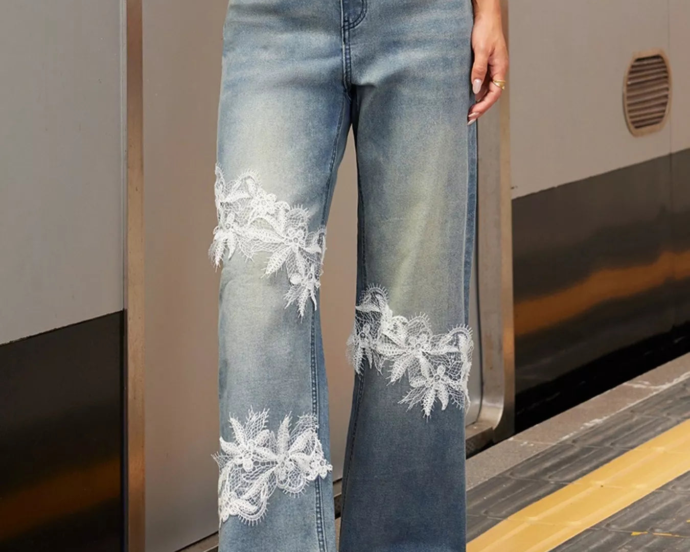 NEWYORKLISTED STYLE COLLECTION: Person wearing blue jeans with white lace details on a train platform.