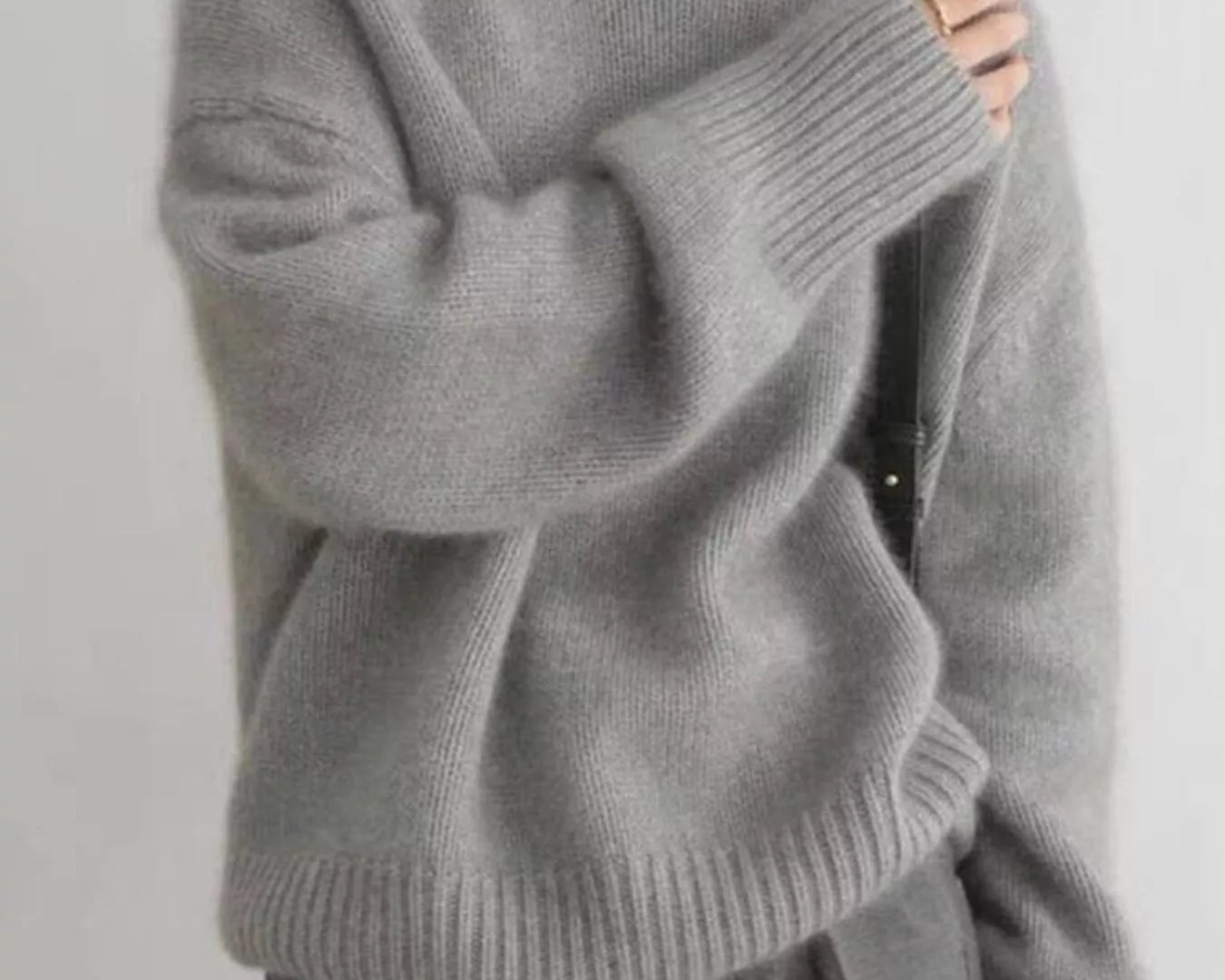 Person wearing a gray turtleneck sweater against a plain background