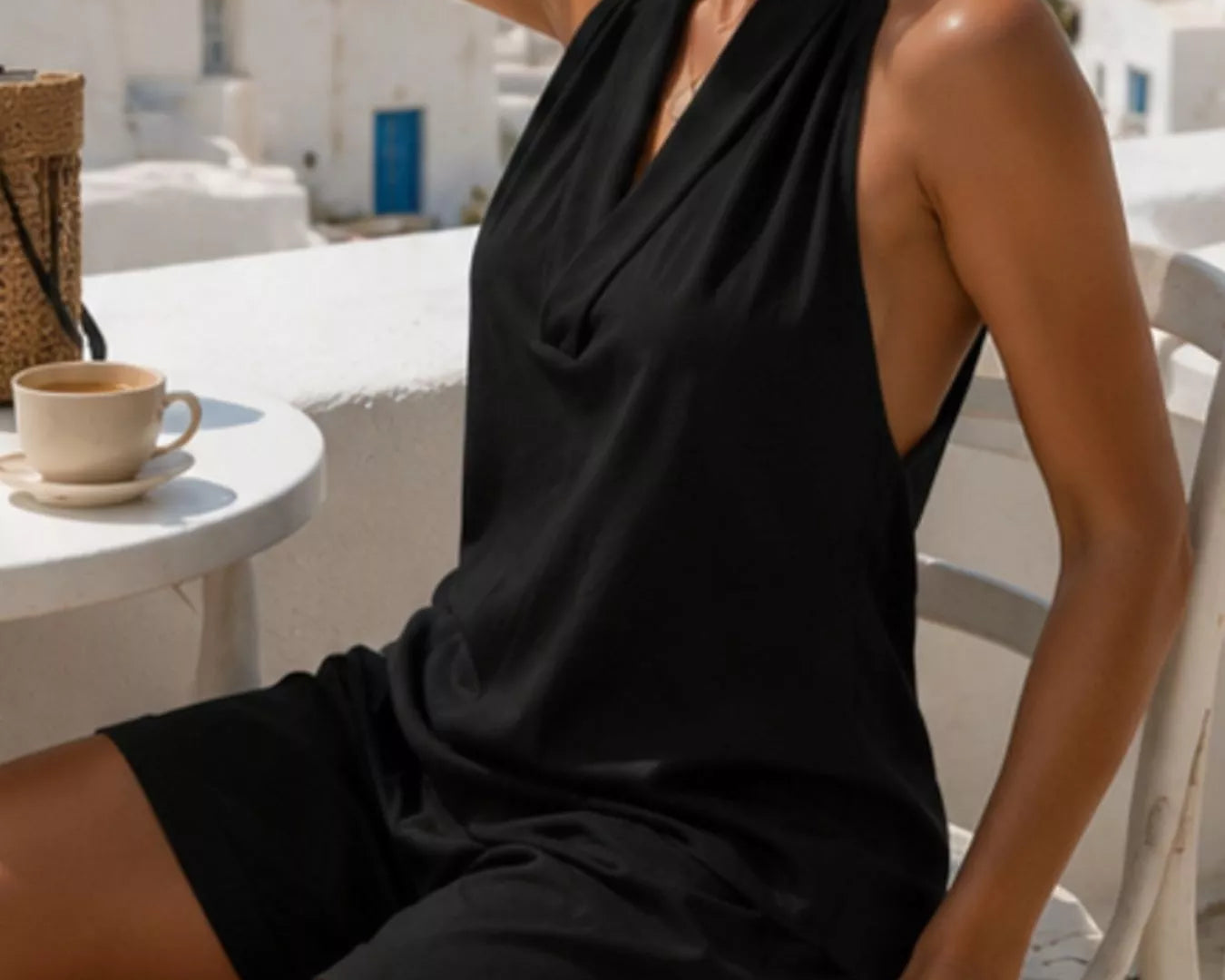 NEWYORKLISTED STYLE COLLECTION: Woman in a black dress sitting on a white chair with a scenic background