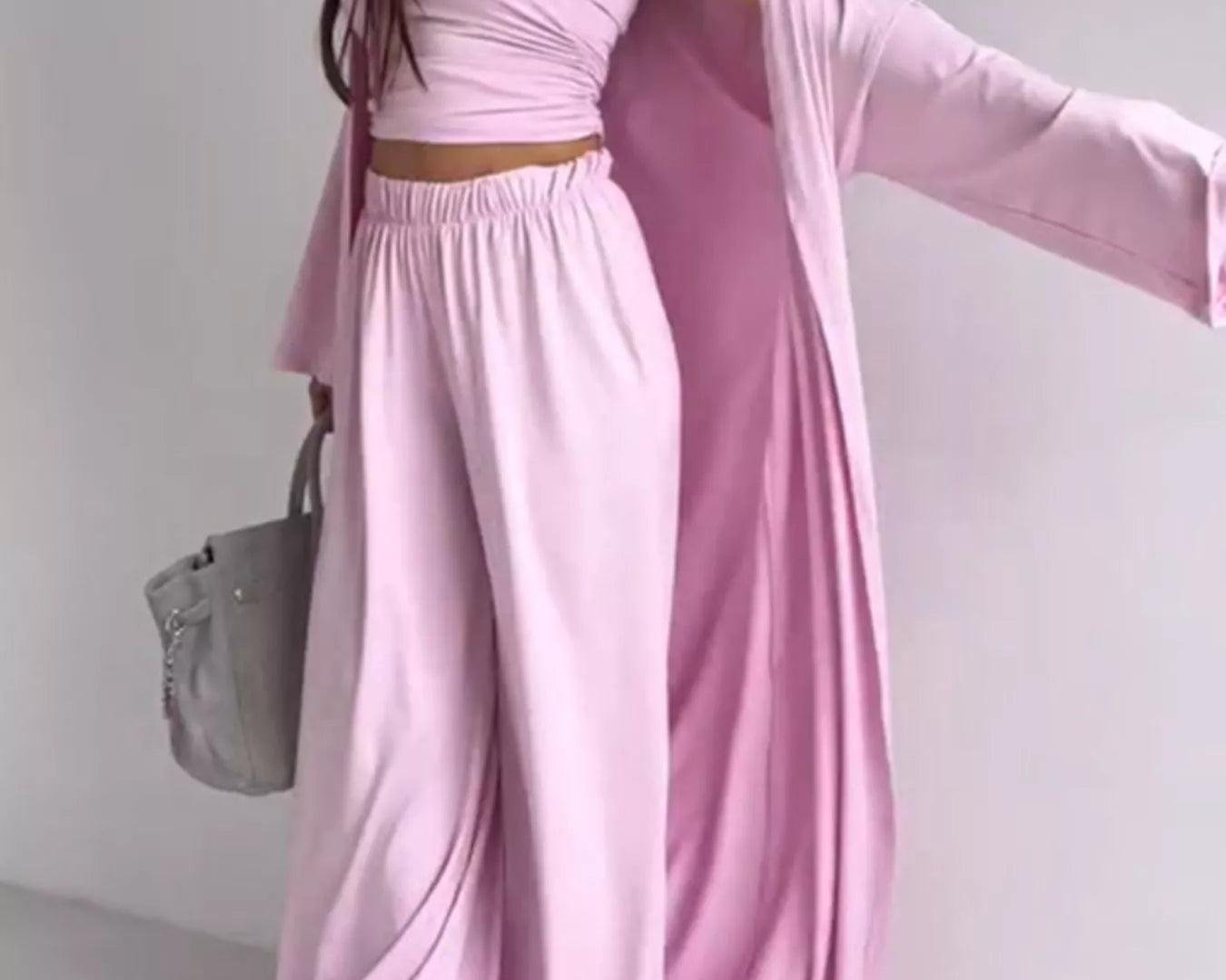 NEWYORKLISTED COMFORT COLLECTION: Woman wearing a pink outfit with a draped fabric over one shoulder against a white background