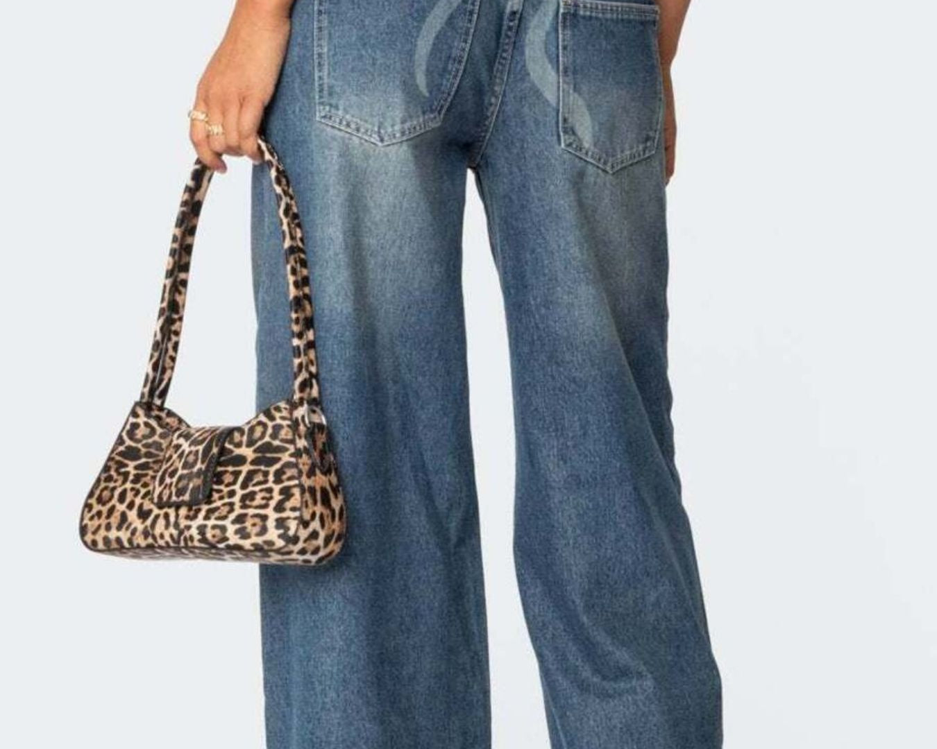 NEWYORKLISTED STYLE COLLECTION: Person wearing blue jeans holding a leopard print handbag on a plain background