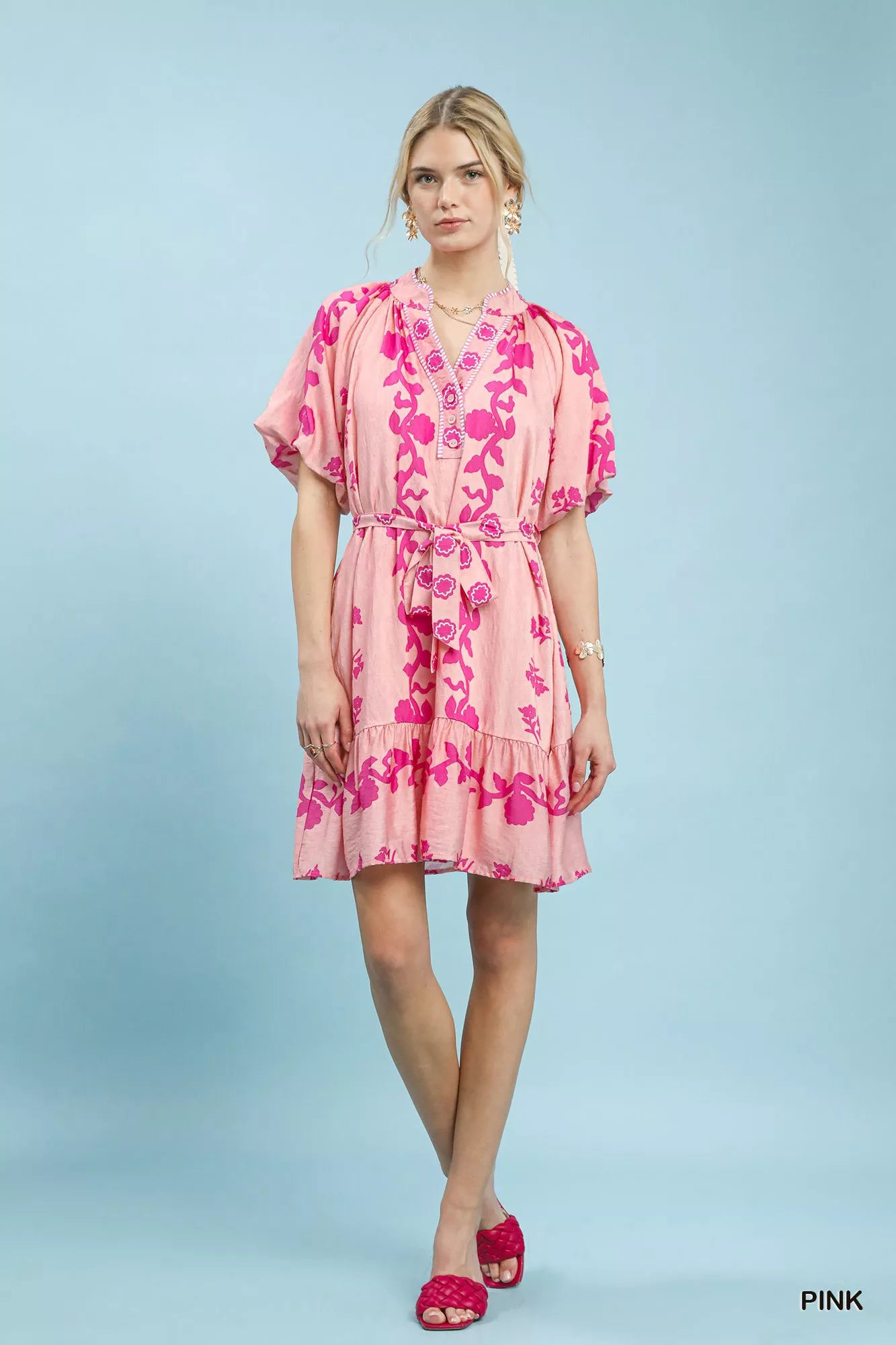 NEWYORKLISTED STYLE COLLECTION: Woman wearing a pink floral dress against a light blue background
