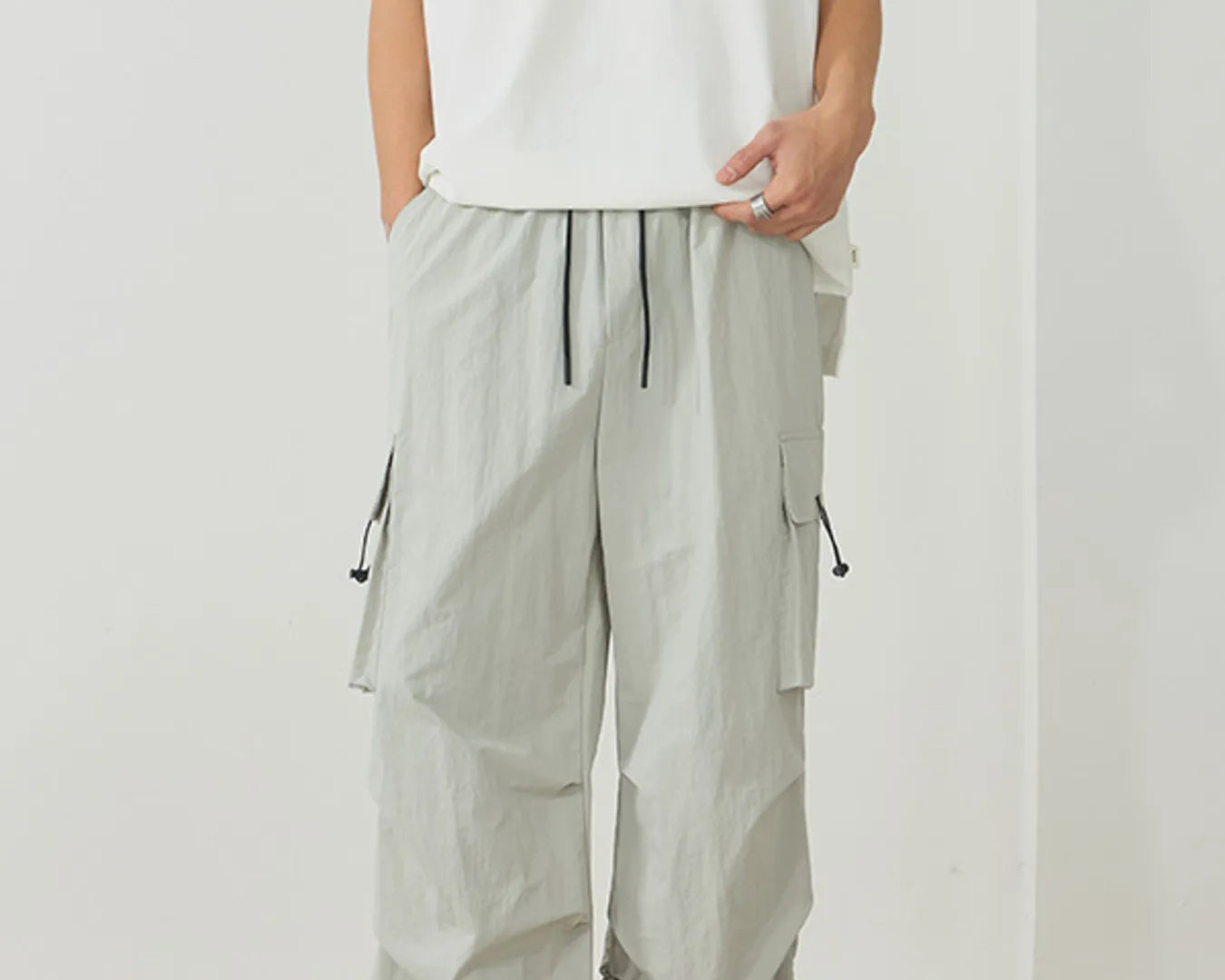 NEWYORKLISTED ATLAS MEN's Collection: Person wearing light gray cargo pants and a white sleeveless top on a plain background