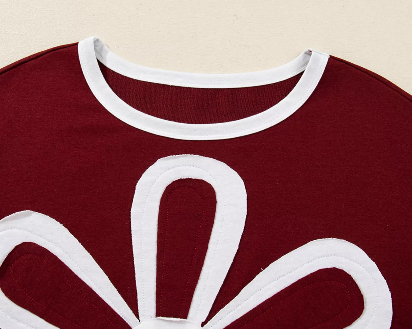 NEWYORKLISTED STYLE COLLECTION: Red garment with a white floral design on a beige background