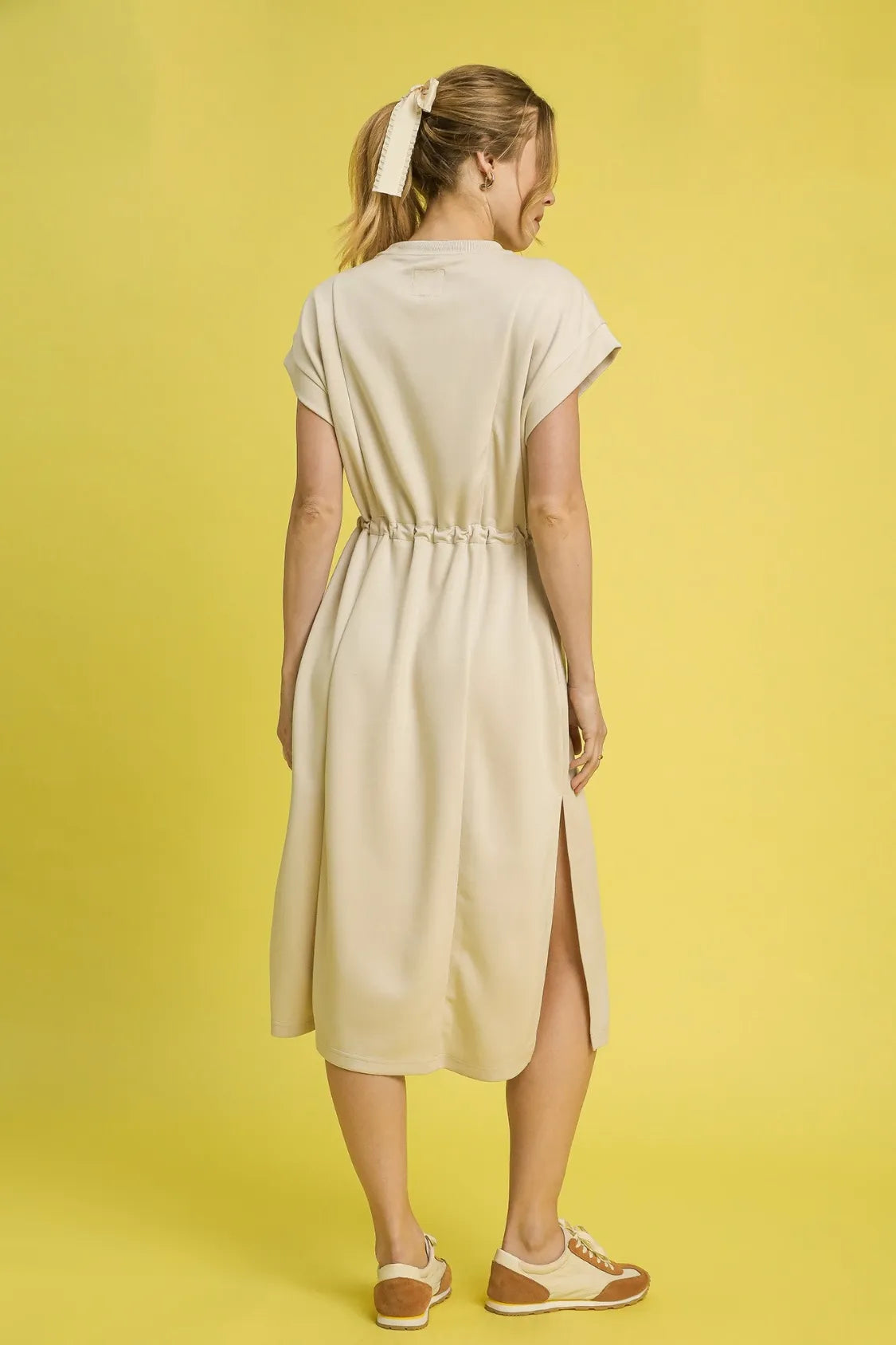 NEWYORKLISTED STYLE COLLECTION: Short Sleeve Midi Tee Dress: Woman wearing a beige dress with a yellow background