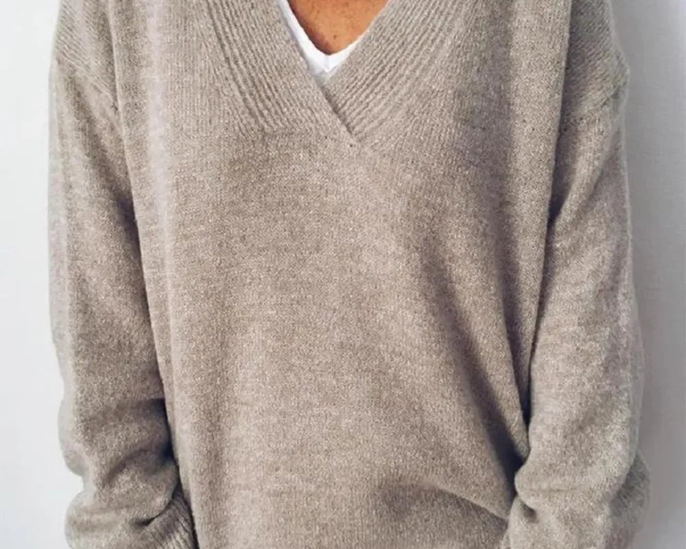 NEWYORKLISTED STYLE COLLECTION: Person wearing a beige sweater over a white shirt against a plain background