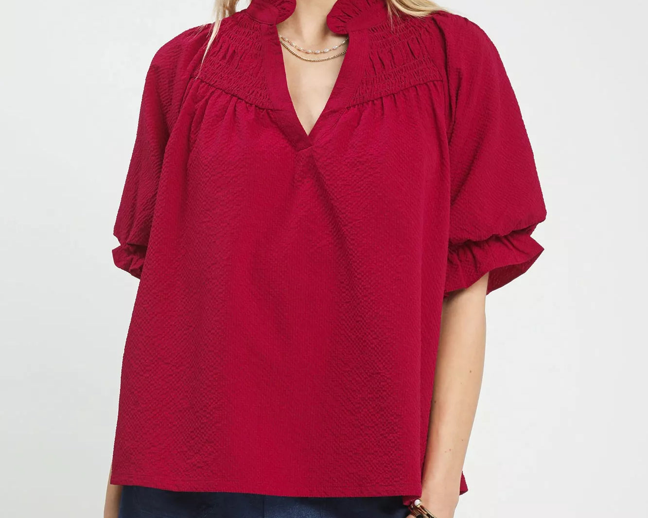 NEWYORKLISTED Style Collection: Woman wearing a red blouse with ruffled collar on a white background