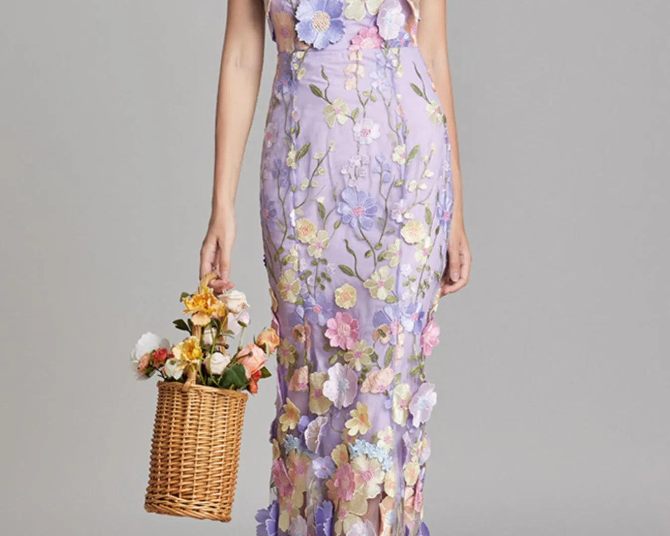 NEWYORKLISTED STYLE COLLECTION: Woman wearing a floral dress holding a basket of flowers against a gray background