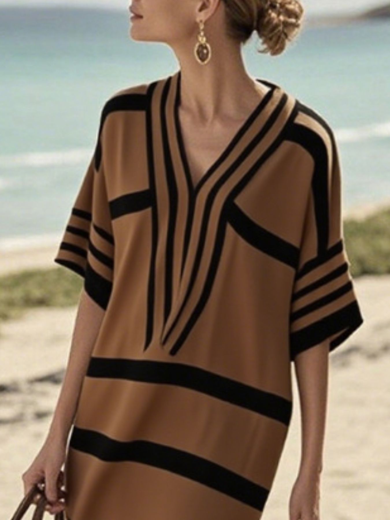 NEWYORKLISTED STYLE COLLECTION: Woman wearing a brown and black striped dress on a beach.