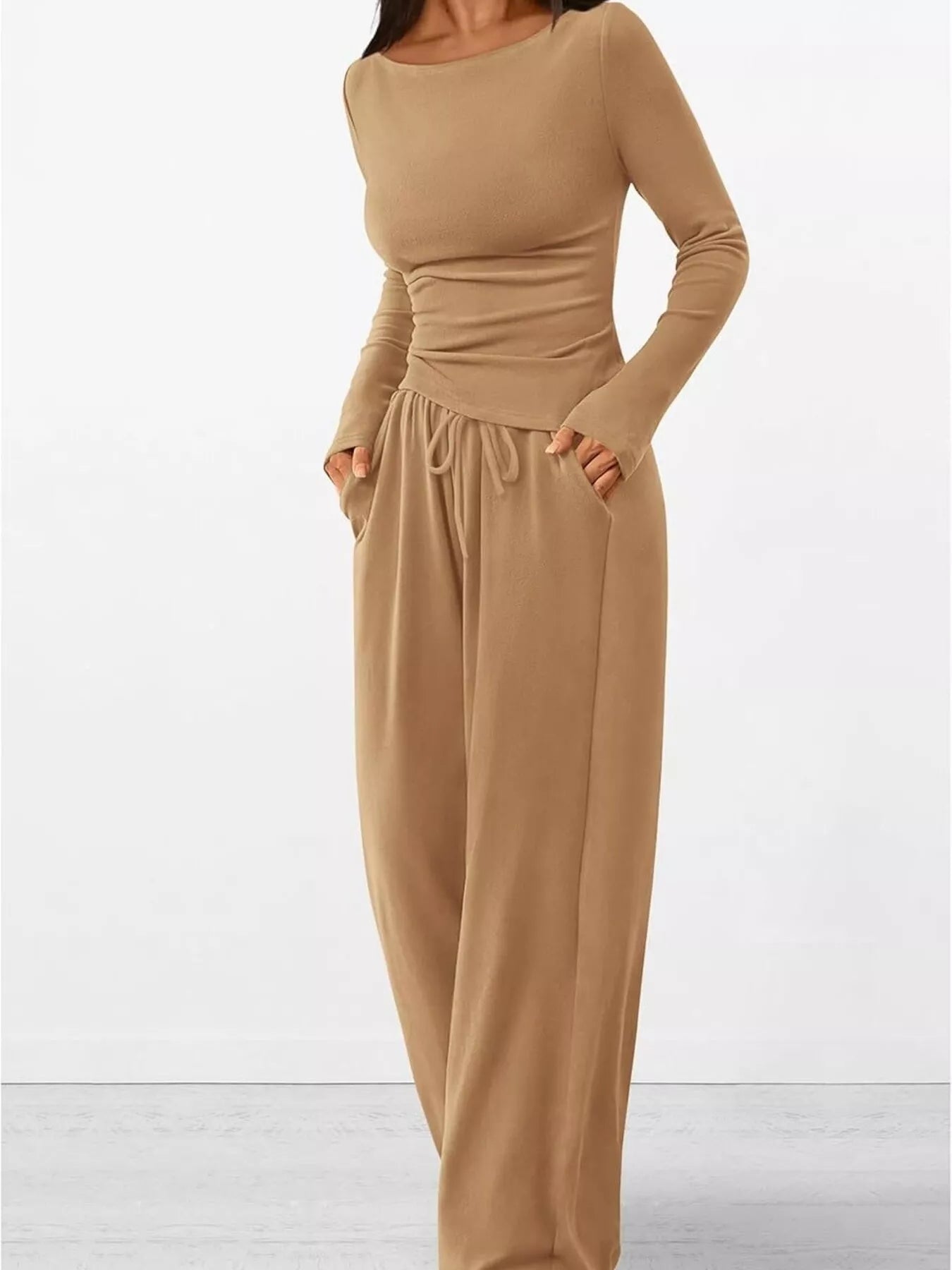 Beige jumpsuit with long sleeves and wide-leg pants on a white background