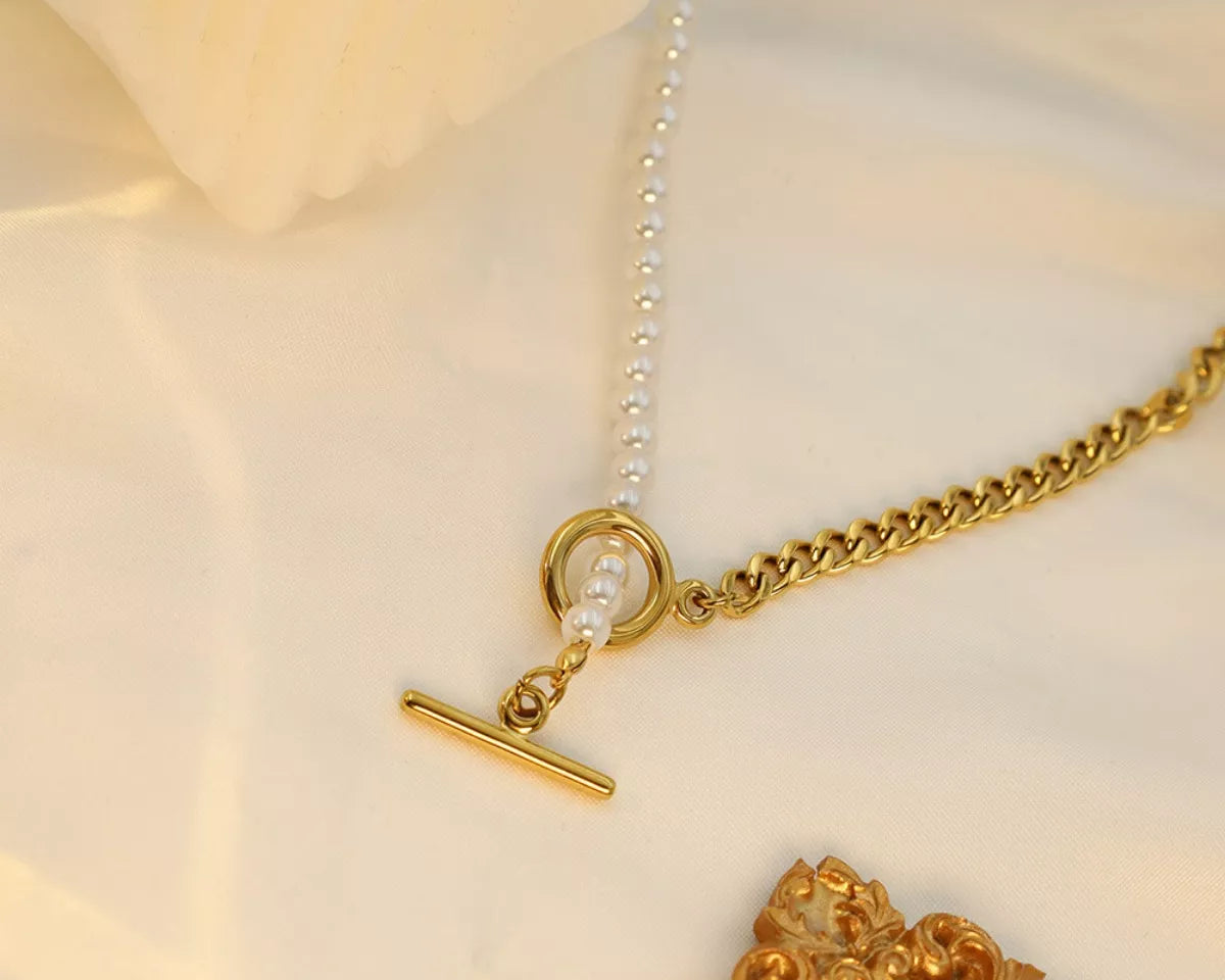 NYLD Glamour Collection by NEWYORKLISTED: Gold necklace with a clasp on a soft beige background