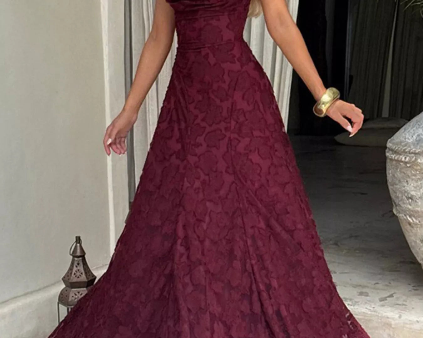 NEWYORKLISTED STYLE COLLECTION: Woman wearing a burgundy lace evening gown indoors.