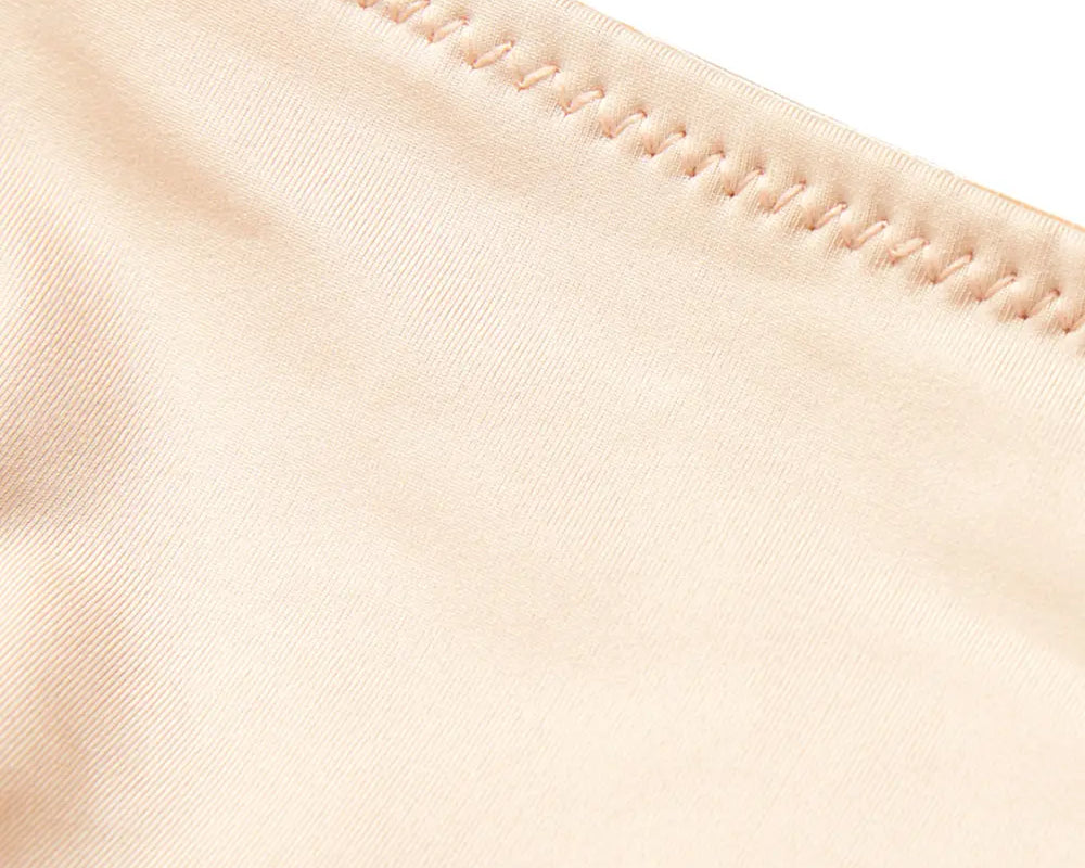 NEWYORKLISTED Intimate Apparel: Close-up of beige fabric with a focus on stitching detail