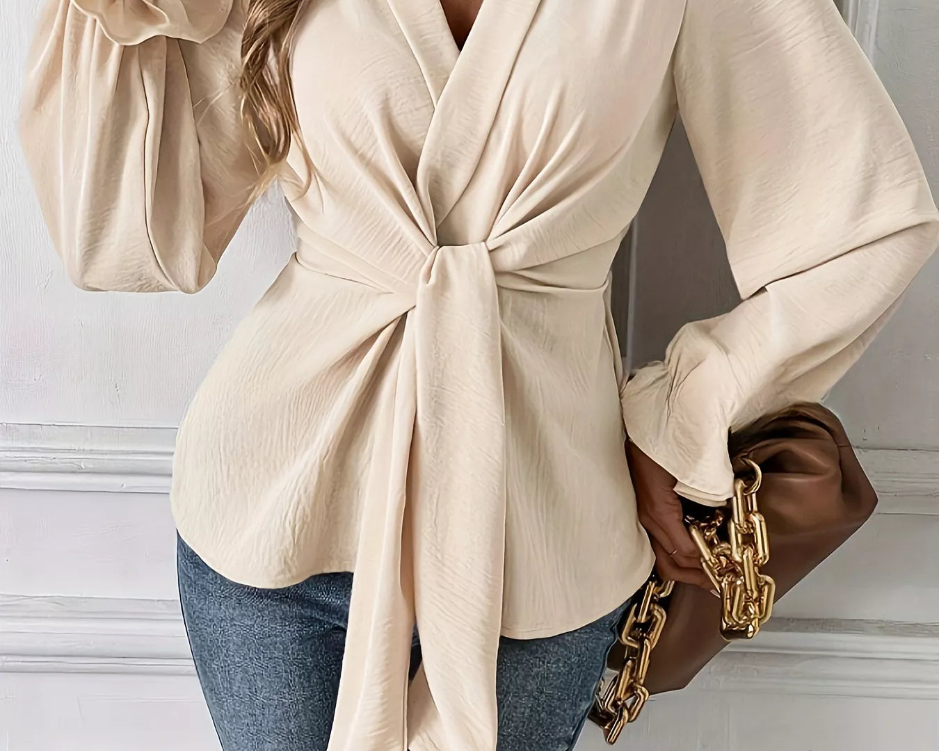 NEWYORKLISTED STYLE COLLECTION: Woman wearing a beige wrap top with blue jeans and a brown handbag.