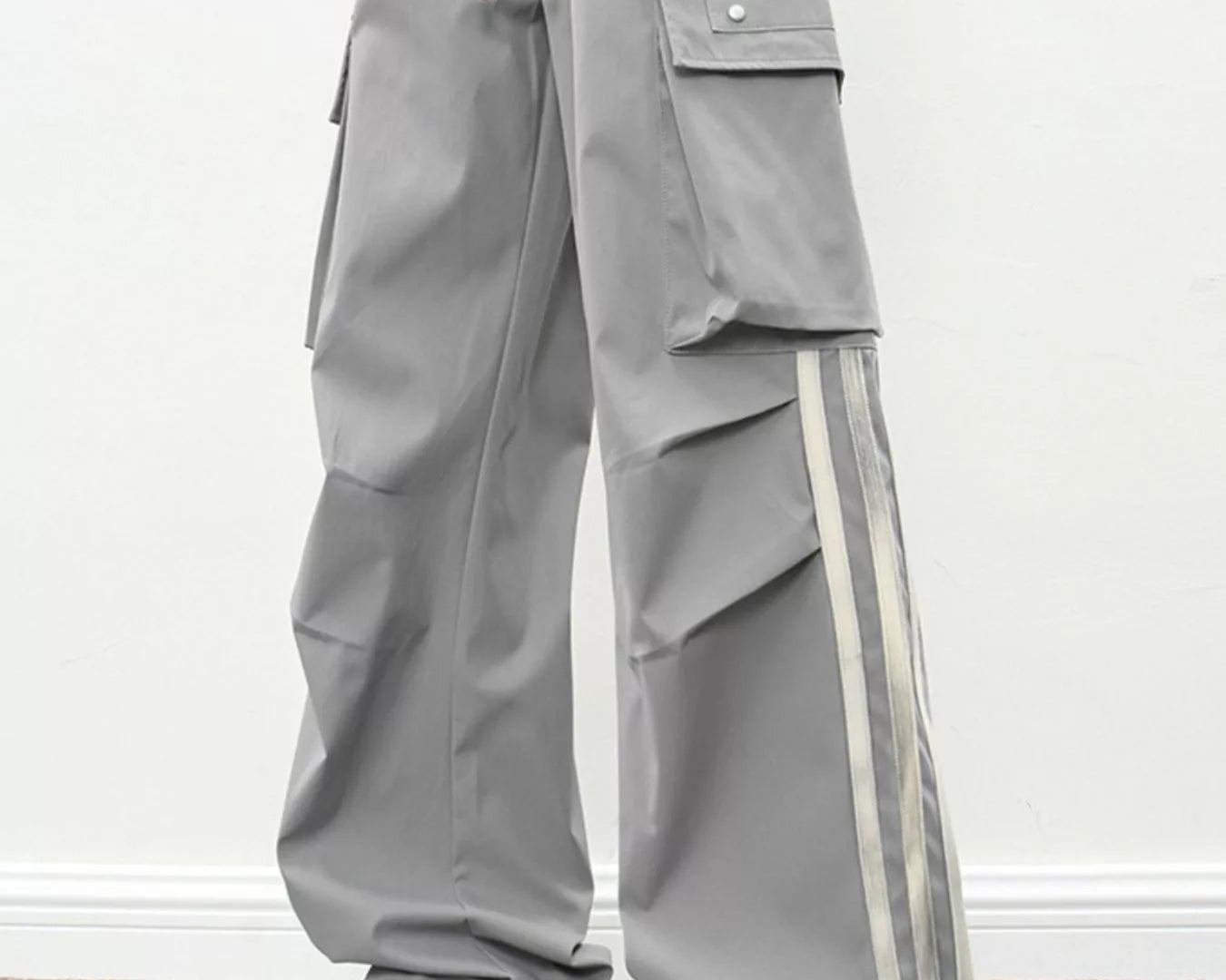 NEWYORKLISTED ATLAS MEN's COLLECTION: Person wearing gray cargo pants with white stripes and white sneakers on a plain background