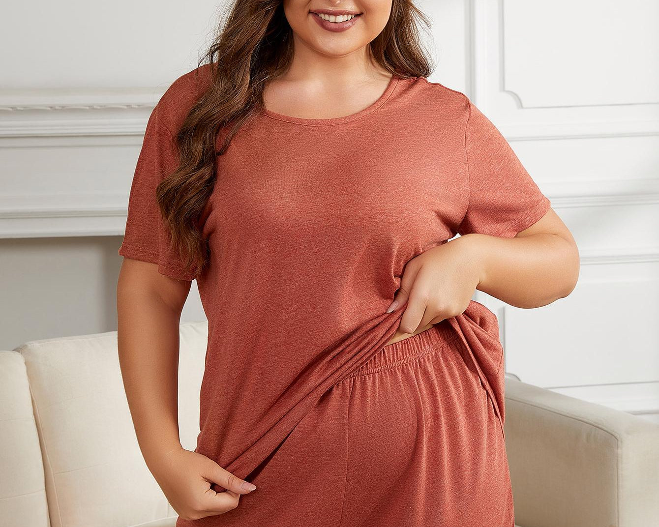 NEWYORKLISTED Intimate Apparel Collection: Woman wearing a terracotta-colored lounge set in a living room.