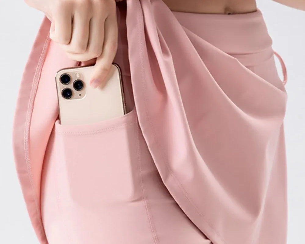 NEWYORKLISTED ACTIVEWEAR COLLECTION: Person wearing a pink skirt with a phone in the pocket on a light gray background