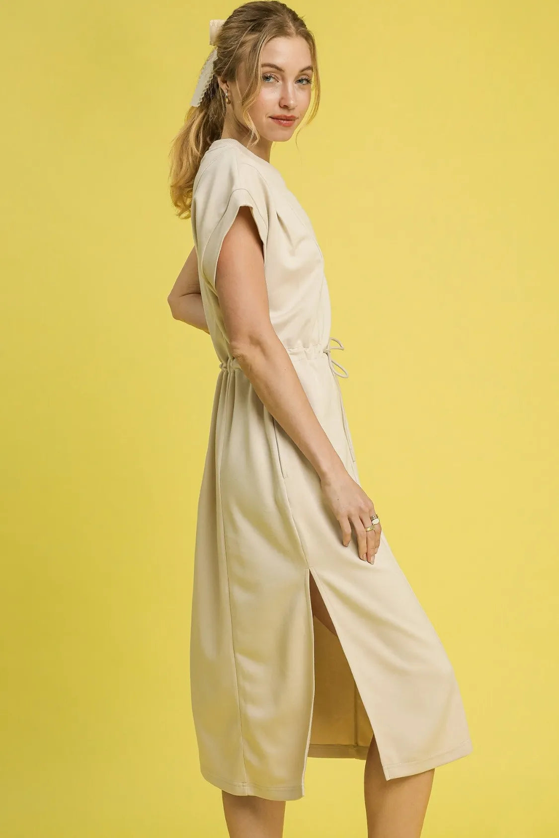NEWYORKLISTED STYLE COLLECTION: Short Sleeve Midi Tee Dress: Woman wearing a light-colored dress against a yellow background