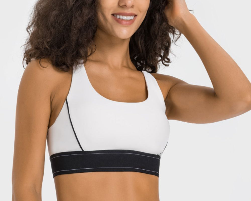 NEWYORKLISTED ACTIVEWEAR COLLECTION: Woman wearing a white sports bra with black waistband on a white background