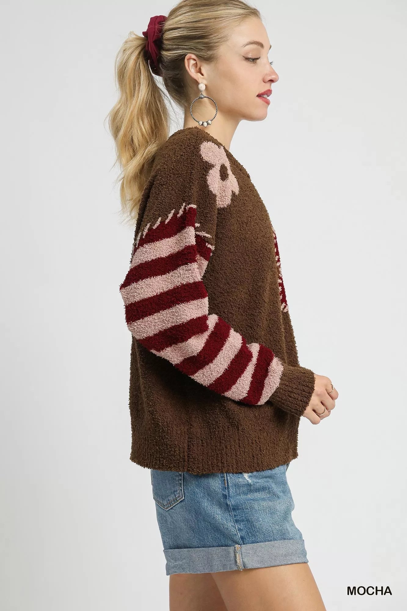 NEWYORKLISTED STYLE COLLECTION: Woman wearing a brown sweater with red and white striped sleeves on a white background