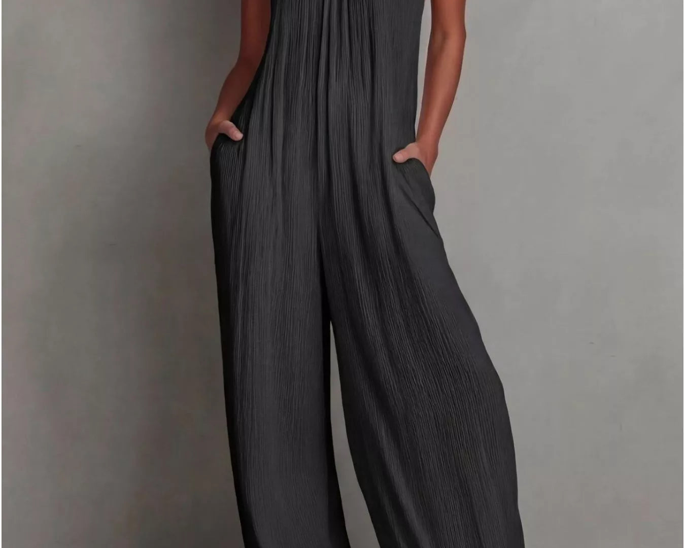 NEWYORKLISTED STYLE COLLECTION: Woman wearing a dark gray jumpsuit against a plain background