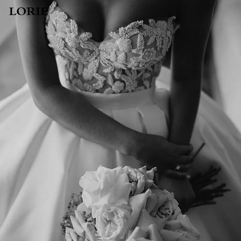 Black and white image of a person wearing a lace wedding dress holding flowers.