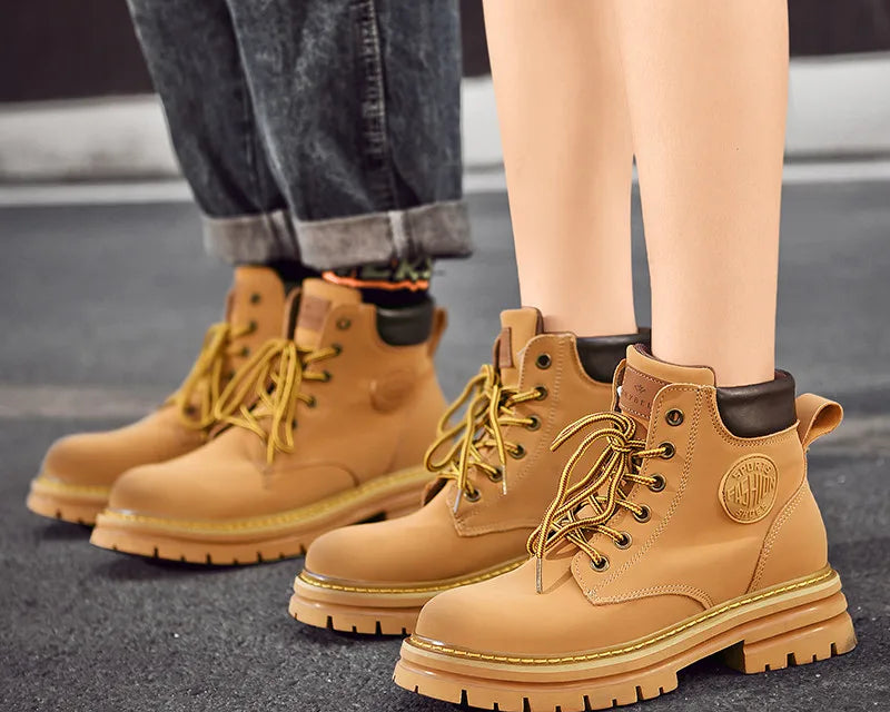 NEWYORKLISTED: Tan work boots with brand logo worn by a person on a dark surface