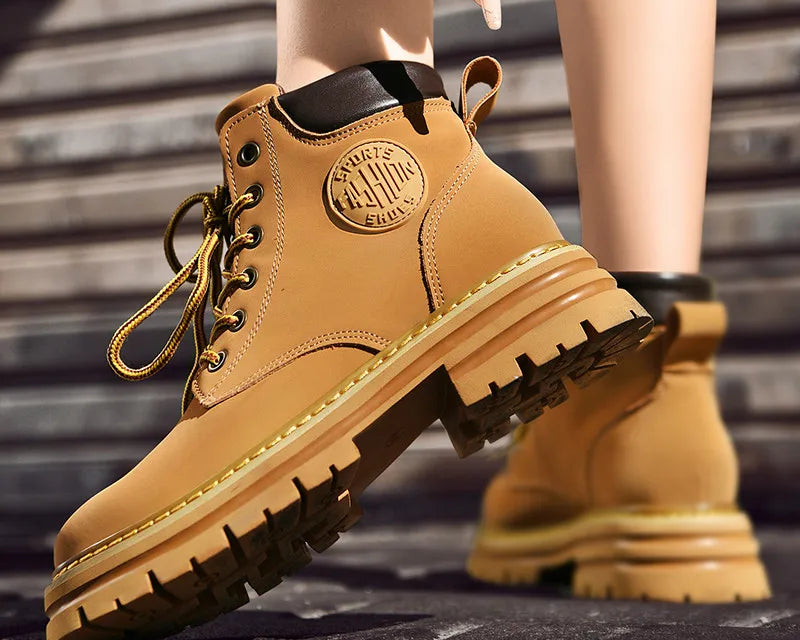 NEWYORKLISTED: Tan work boots with brand logo on a blurred outdoor background