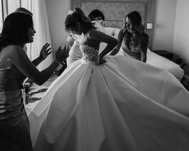 Black and white photo of a bride getting ready with friends in a hotel room.
