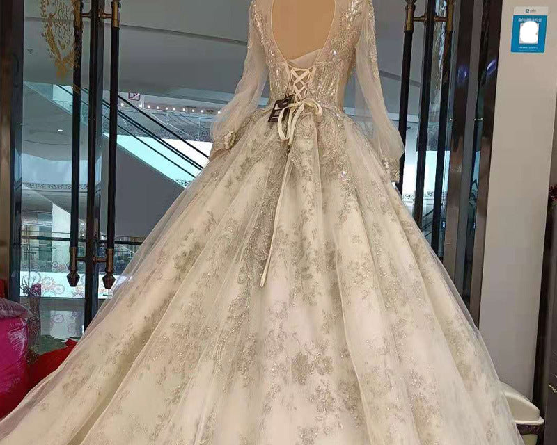 Beige wedding dress with intricate detailing on a mannequin in an indoor setting.