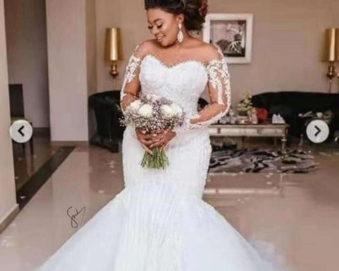 Woman in a white wedding dress holding flowers in a room.