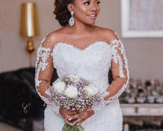 Bride in a white wedding dress holding a bouquet indoors.
