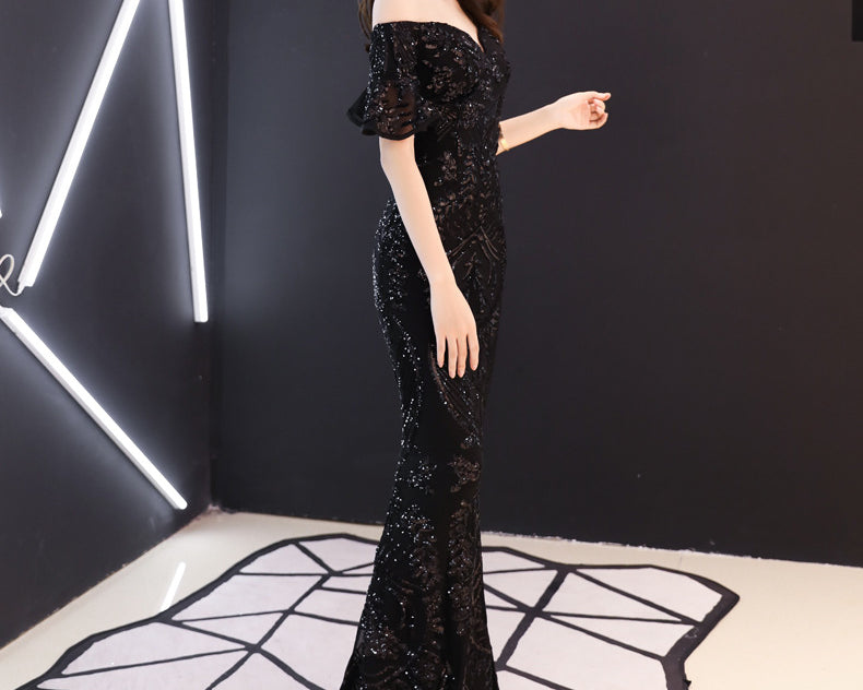 Woman in a black sequin dress standing in a modern interior setting with geometric floor design.