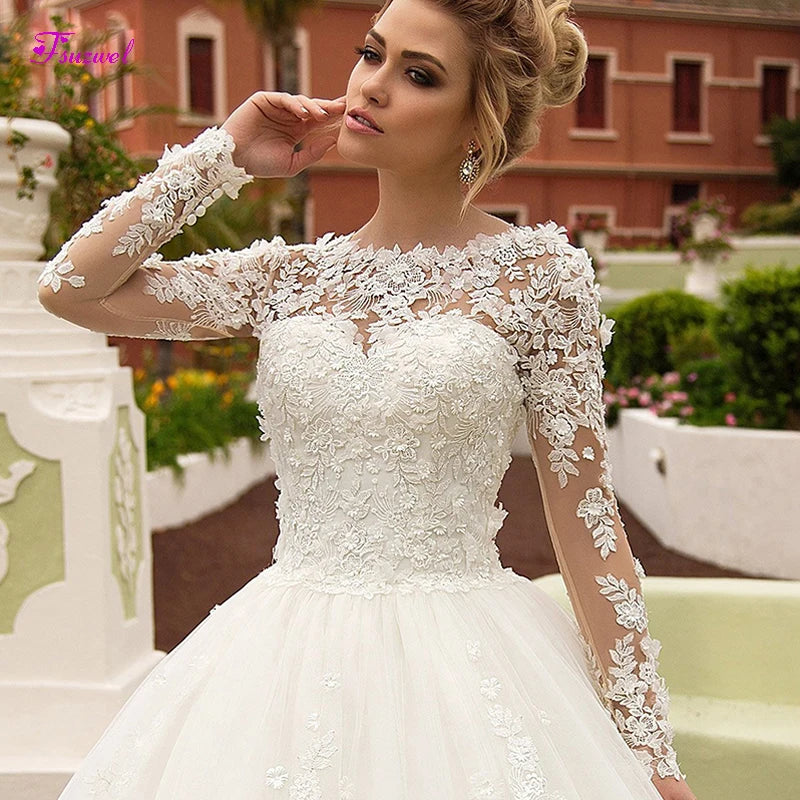 NEWYORKLISTED ELEGANT BRIDE COLLECTION: Woman wearing a white lace wedding dress with long sleeves in an outdoor setting.