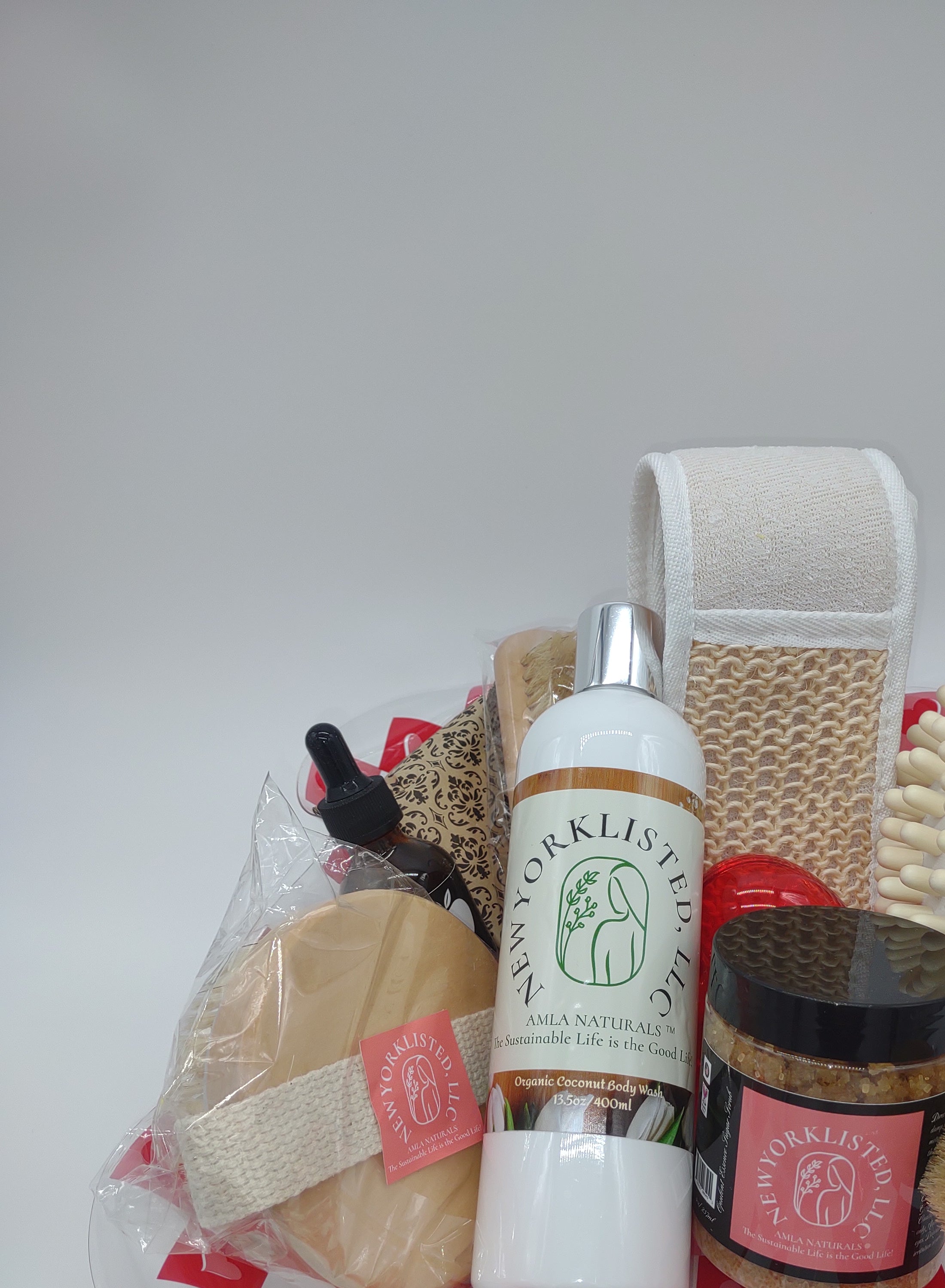 NEWYORKLISTED Valentine’s Day Luxury Spa Gift Basket, Set of bath products including a bottle, brush, and loofah on a white background