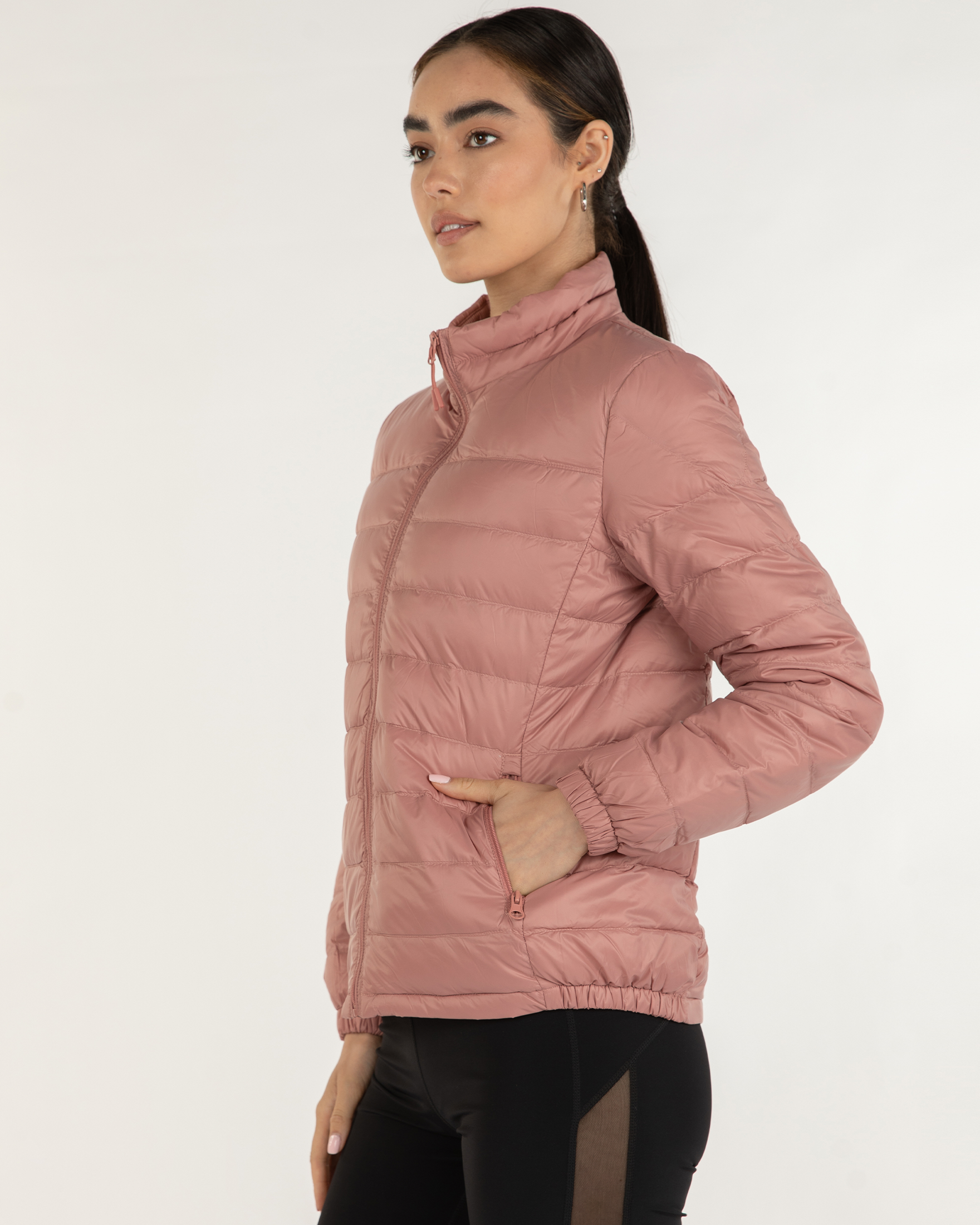 Woman wearing a pink puffer jacket on a white background