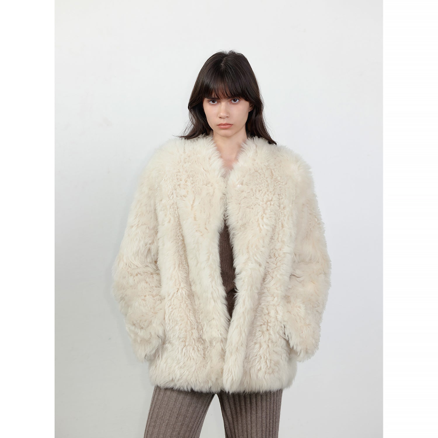 NEWYORKLISTED STYLE COLLECTION: Person wearing a fluffy white coat against a plain background