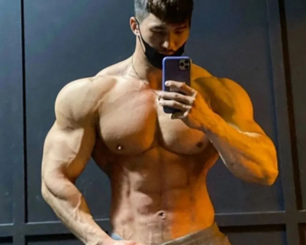 NEWYORKLISTED ATLAS MEN's COLLECTION: Muscular man taking a mirror selfie against a dark wall.