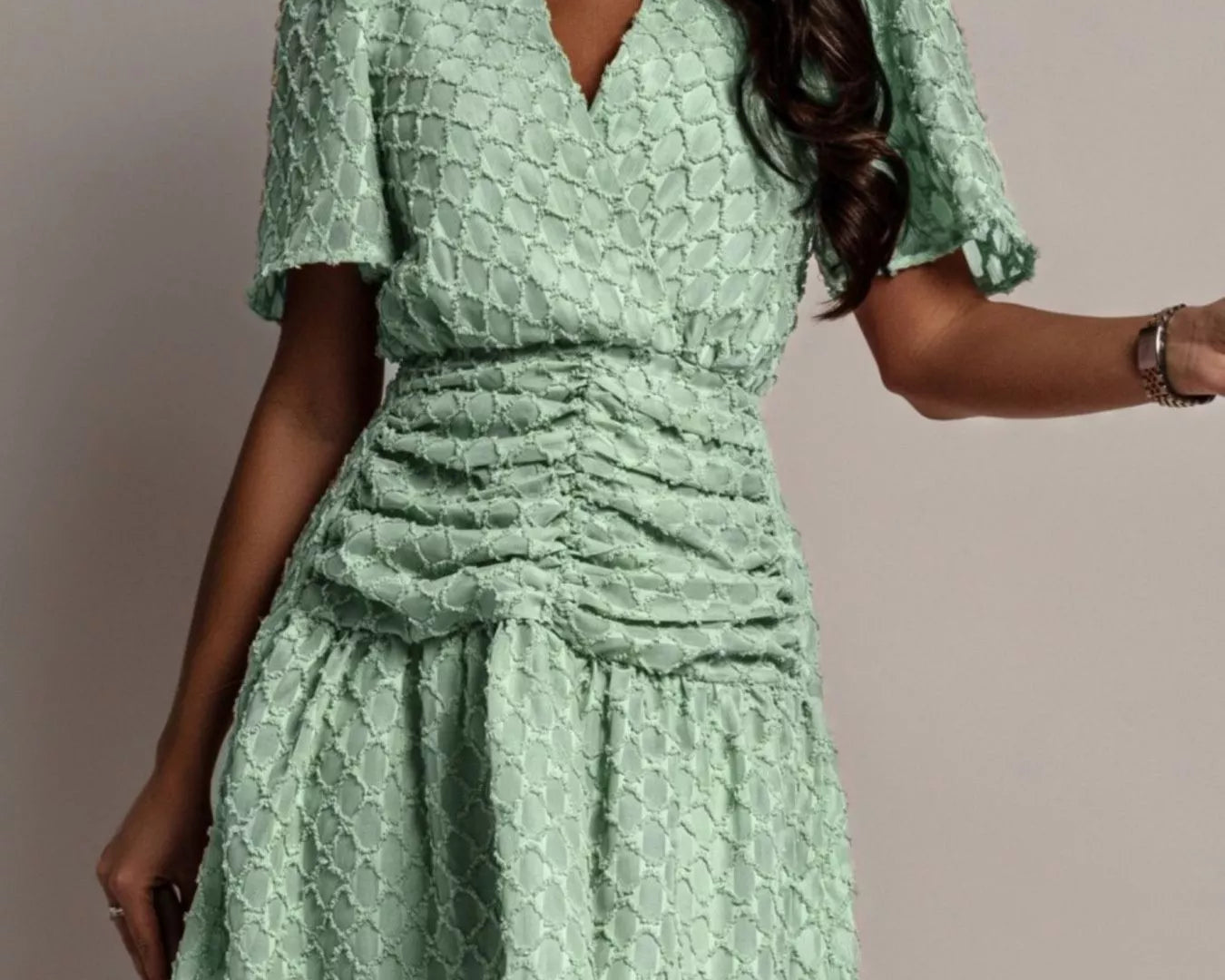NEWYORKLISTED STYLE COLLECTION: Woman wearing a green textured dress against a neutral background