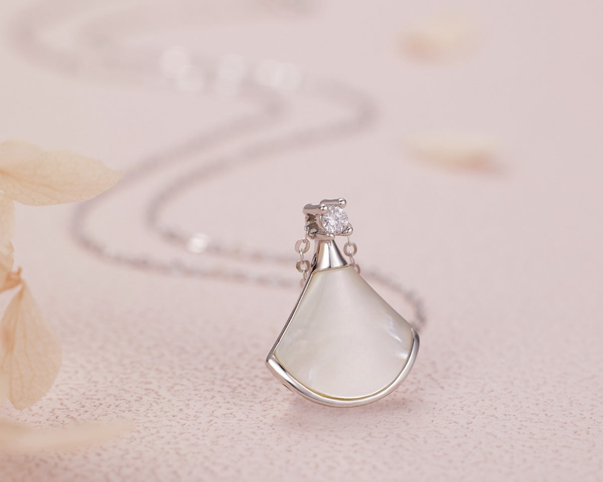 NYLD Glamour By NEWYORKLISTED: Silver pendant with a teardrop-shaped white stone on a soft pink background