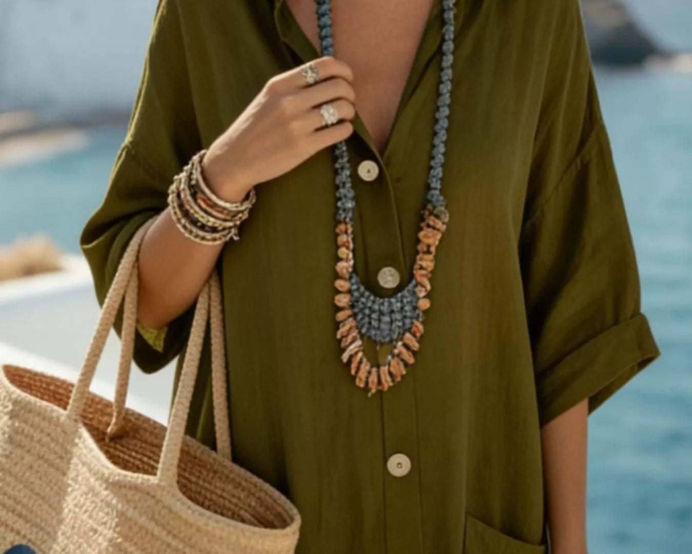 NEWYORKLISTED STYLE COLLECTION: Woman in an olive green dress holding a woven bag with a scenic background