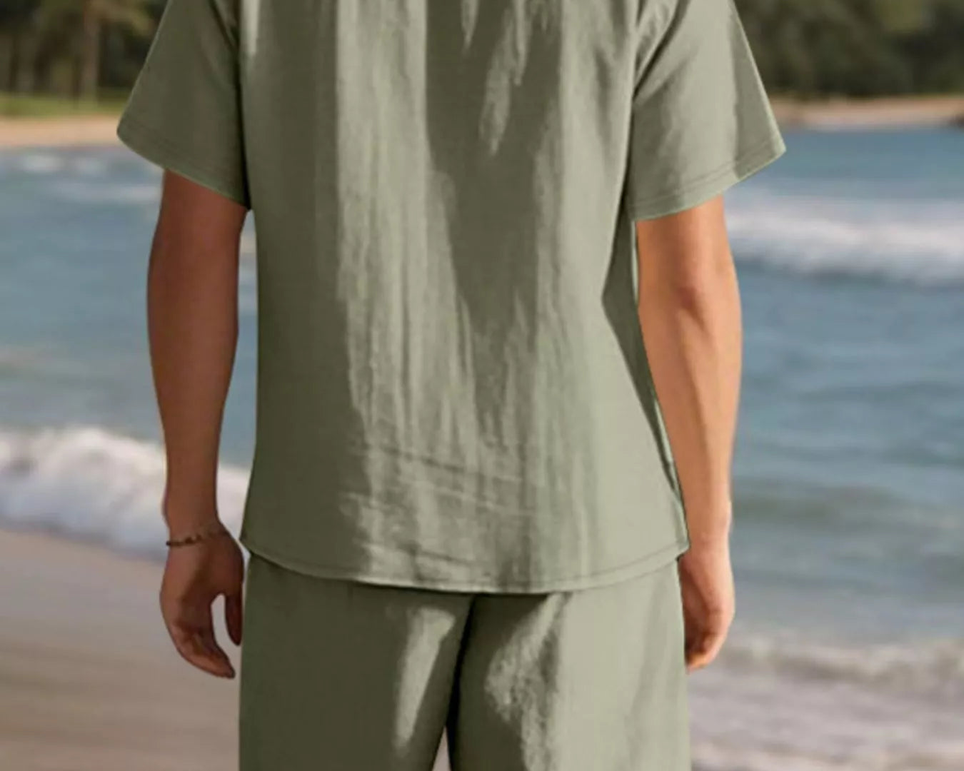 NEWYORKLISTED ATLAS MEN'S COLLECTION: Person wearing a green shirt and shorts standing on a beach with mountains in the background