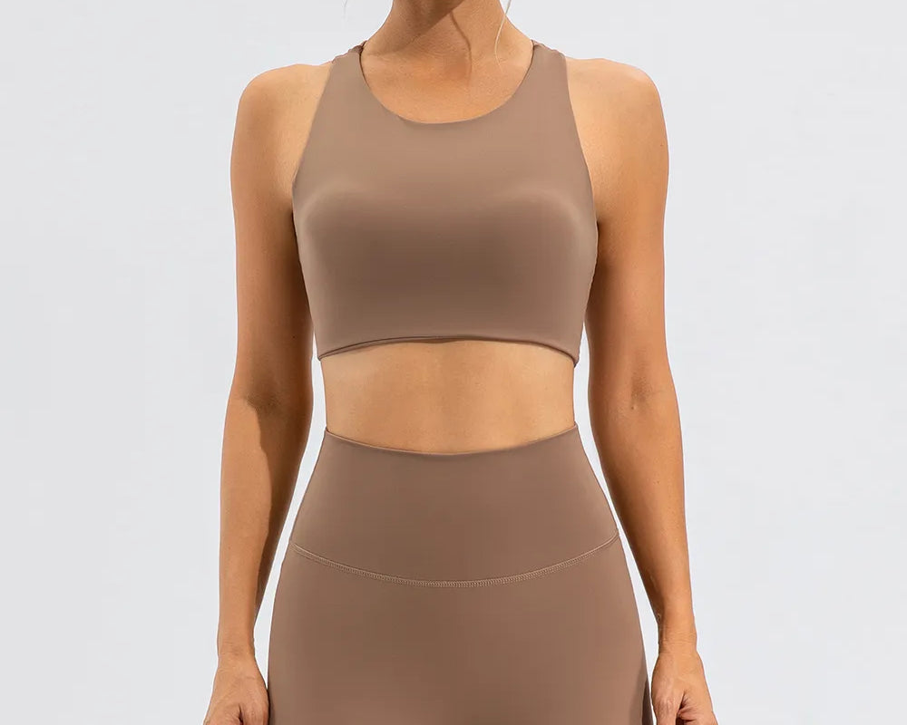 NEWYORKLISTED ACTIVEWEAR COLLECTION: Woman wearing a brown sports bra and leggings set on a white background