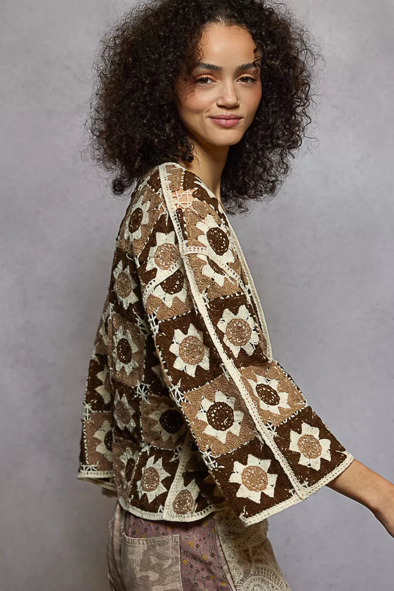 NEWYORKLISTED STYLE COLLECTION: Woman wearing a patterned brown and beige shawl against a gray background